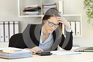 Worried bookkeeper calculating expenses at office photo