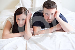 Worried and bored lovers couple after a fight lying in bed