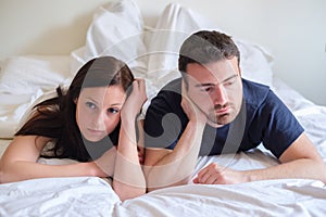 Worried and bored lovers couple after a fight lying in bed