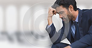 Worried business man sitting against office background