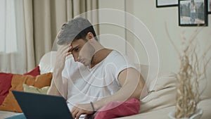 Worried business man working on laptop computer at couch. Upset man