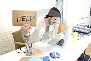 Worried businessman in cool hipster beanie look holding help sign working in stress at home office