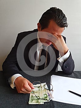 worried businessman with hand on his face and Chinese money on the table