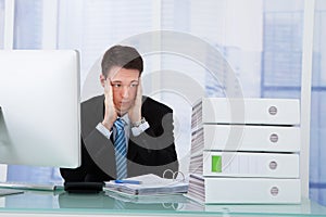 Worried businessman looking at binders on desk