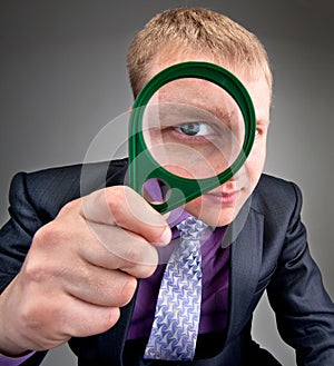 Worried businessman looking through magnifier lens