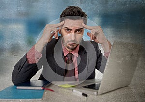 Worried businessman at office suffering headache working on computer desperate in work stress