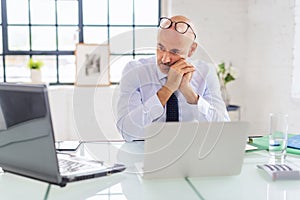 Worried businessman sitting at the office and using laptop for work