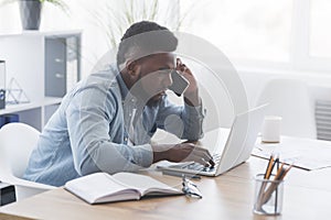 Worried businessman talking on cellphone and looking at laptop screen