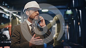 Worried businessman talking smartphone at metallurgy production close up.