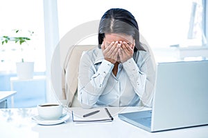 Worried businesswoman covering face