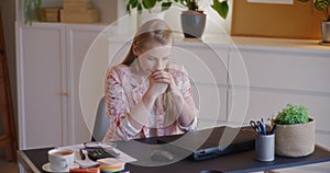 Worried businesswoman with hands clasped at desk