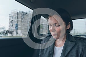 Worried businesswoman sitting at car back seat