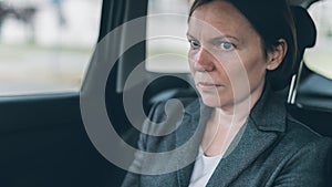 Worried businesswoman sitting at car back seat