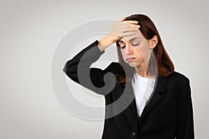Worried businesswoman in a sleek black suit with her hand on her forehead displaying a gesture of forgetfulness photo