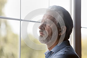 Worried concerned elderly male pensioner stand alone look through window