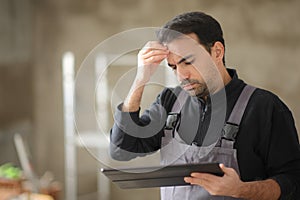 Worried construction worker checking tablet