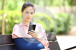 Worried convalescent woman checking phone in a park photo