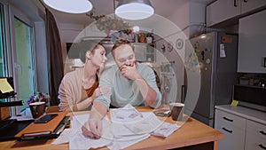 Worried couple looking at their bills in the kitchen at home. Man and woman calculating domestic accounts.