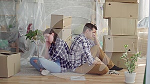 Worried couple middle-aged man and woman sitting in the middle of boxes to move