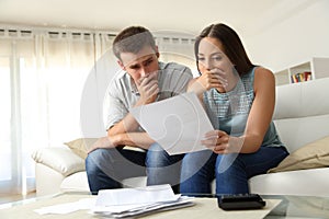 Worried couple reading a letter at home