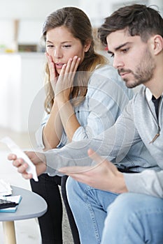 worried couple reading letter sitting at home