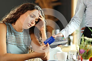 Worried customer paying expensive bill in a restaurant