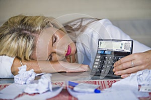 Worried and desperate blond woman calculating domestic money expenses doing paperwork and bank bills accounting with calculator su