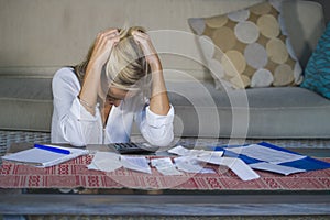 Worried and desperate blond woman calculating domestic money expenses doing paperwork and bank bills accounting with calculator su