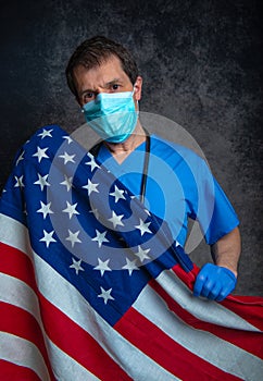 Worried doctor wearing face mask and holding the American flag.