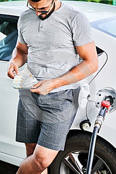 Worried driver counting how much money he must spend on fuel.