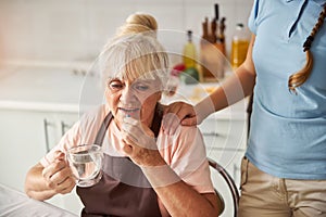 Disturbed grandma taking her medication with water photo