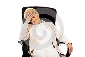Worried elderly business woman sitting on armchair