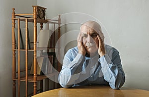 Worried elderly man with his head in his hands photo