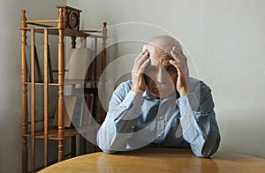Worried elderly man with his head in his hands photo