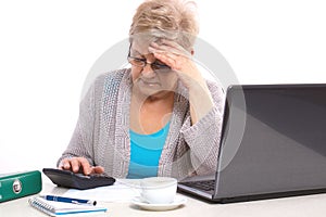 Worried elderly senior woman counting utility bills at her home, financial security in old age