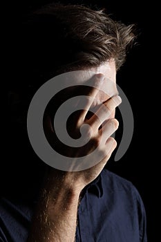 Worried or embarrassed man on black photo