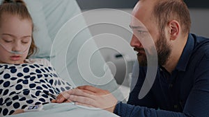 Worried emotional father crying beside sick daughter waiting for healthcare treatment