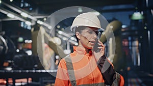 Worried engineer calling cellphone at workshop in protective helmet close up.