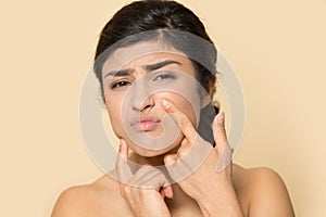 Worried ethnic woman touch skin squeeze pimple