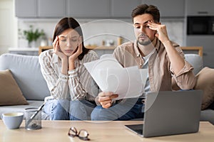 Worried european couple with paperwork and laptop