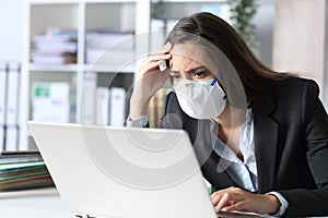 Worried executive with mask reading bad news on laptop photo