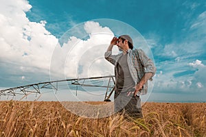 Worried farmer in barley field on a windy day