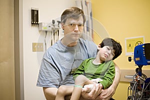 Worried father holding his sick son at hospital
