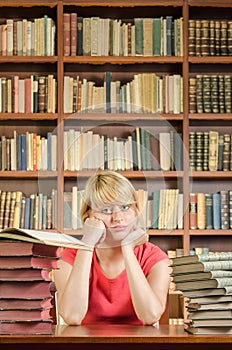 Worried female student in library with elbows on the table