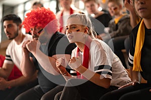 Worried football fans supproting German national team in live soccer match at stadium.