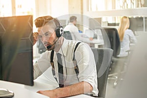 Worried or frustrated business man with headset working on computer in office.