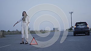 Worried girl tries to stop passing cars on roadway out of city