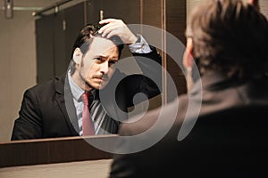 Worried Hispanic Business Man Looking At Hairline In Office Restrooms