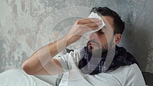 Worried ill man wiping forehead with tissue