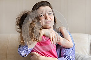 Worried loving mother hug, tightly hold crying baby sitting in her hands. young woman pity upset girl. photo